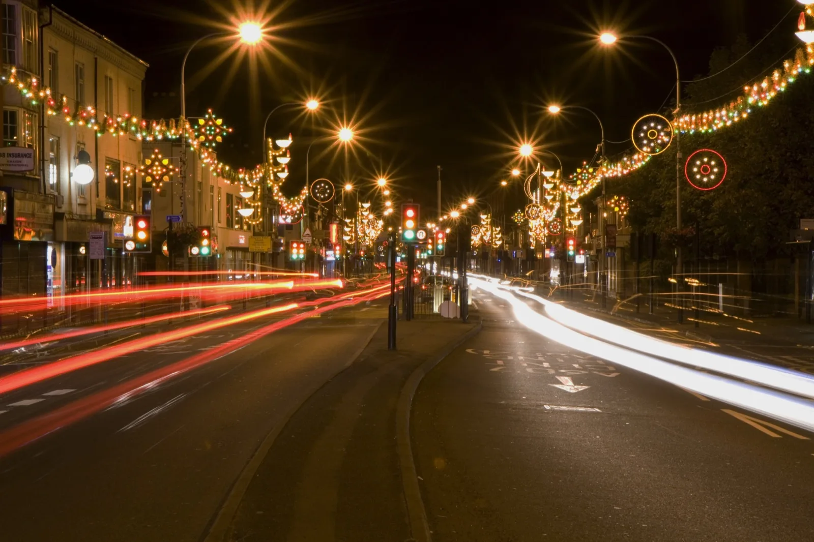 Strings of Diwali lights across Belgrave Road in Leicester at night, with streaks of light from passing cars.