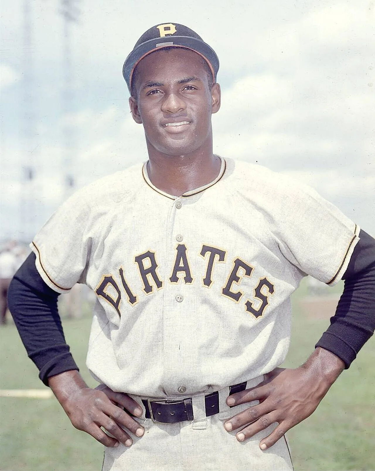 Roberto Clemente in a Pittsburgh Pirates uniform in 1957, hands on hips, smiling